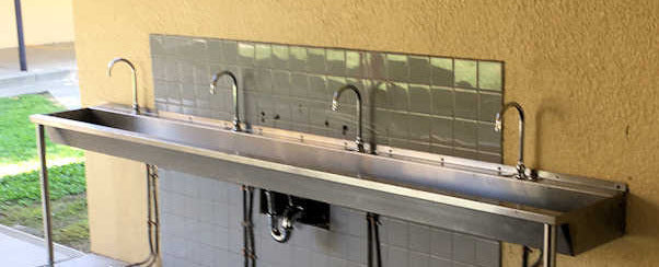 Outdoor stainless steel trough sink with 4 faucets.